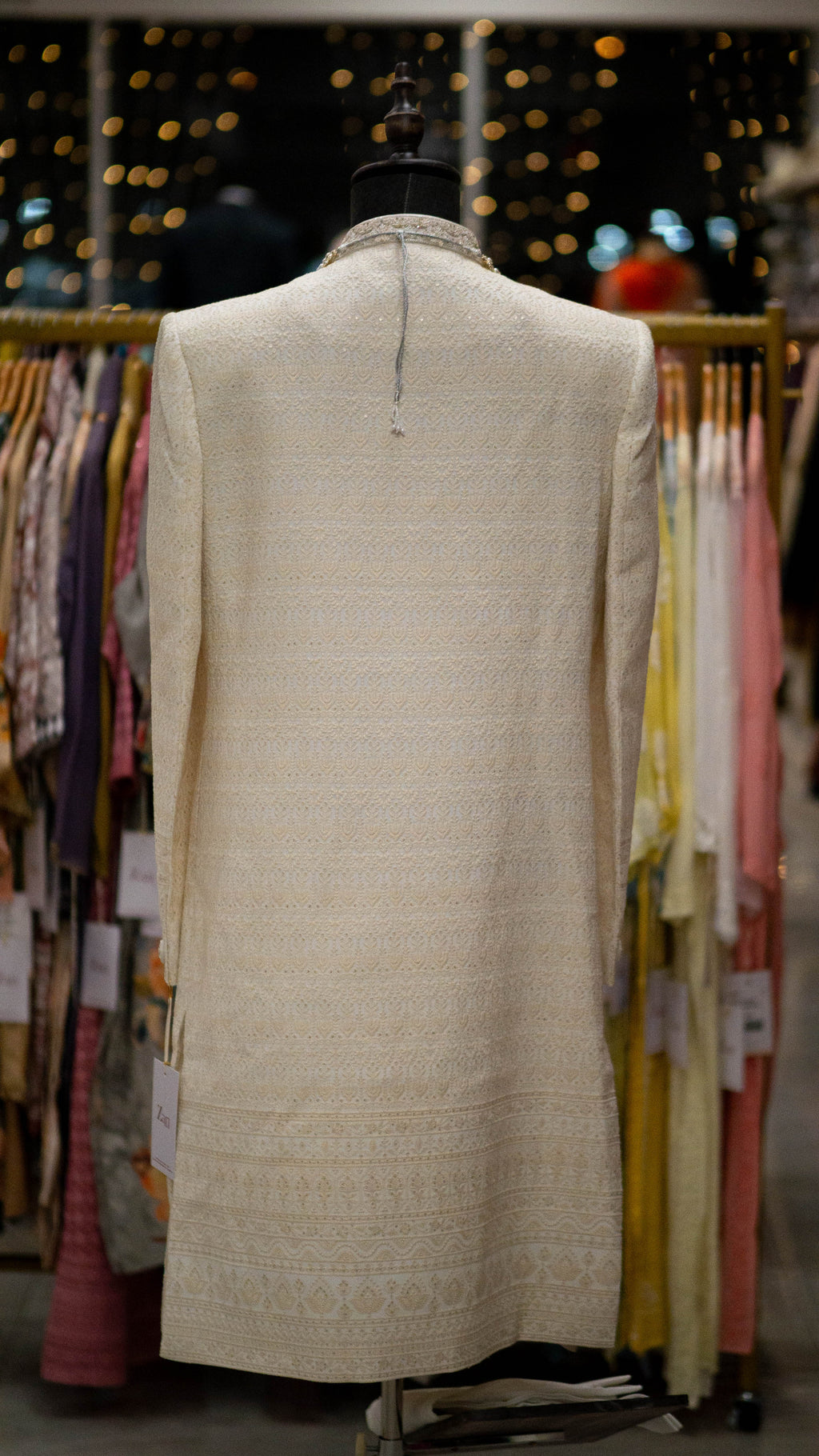 Ivory color Sherwani on a mannequin against a blurred clothing store background