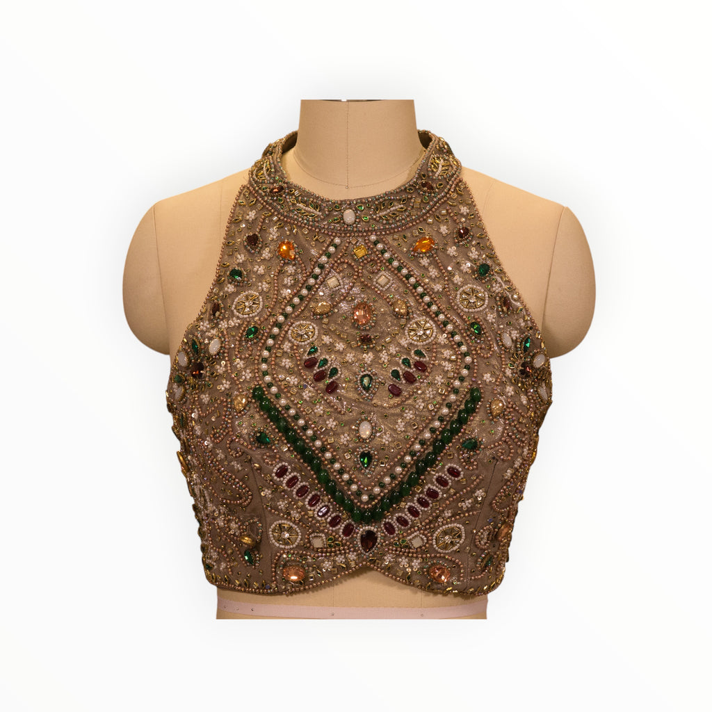 Zari Designs beige halter neck blouse featuring intricate multi-colored gemstone and pearl embroidery on a mannequin.