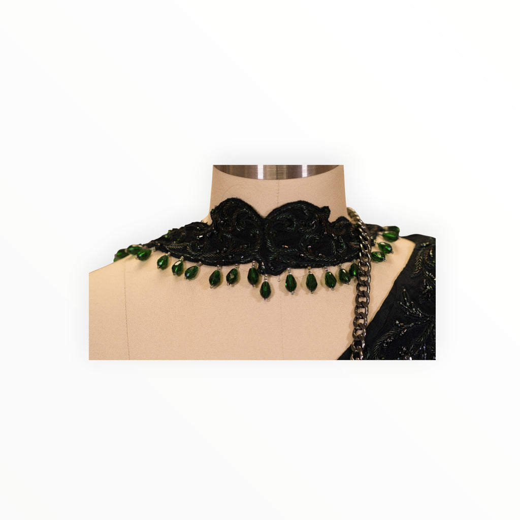 Zari Designs black drape saree featuring an intricate embroidered choker neckline with hanging emerald green beads.