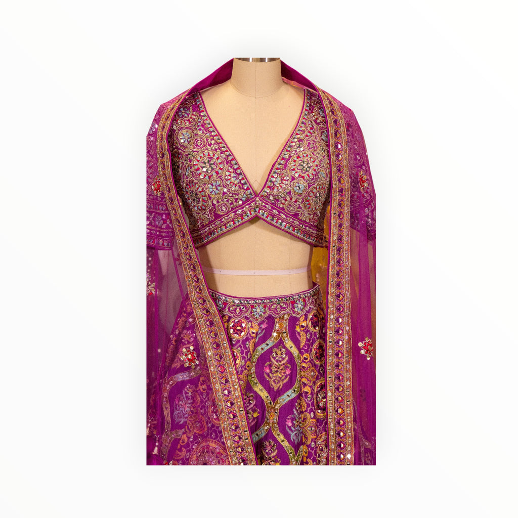 Zari Designs Carnival Lehnga in vibrant magenta with intricate mirror work, embroidery, and a matching sheer dupatta.