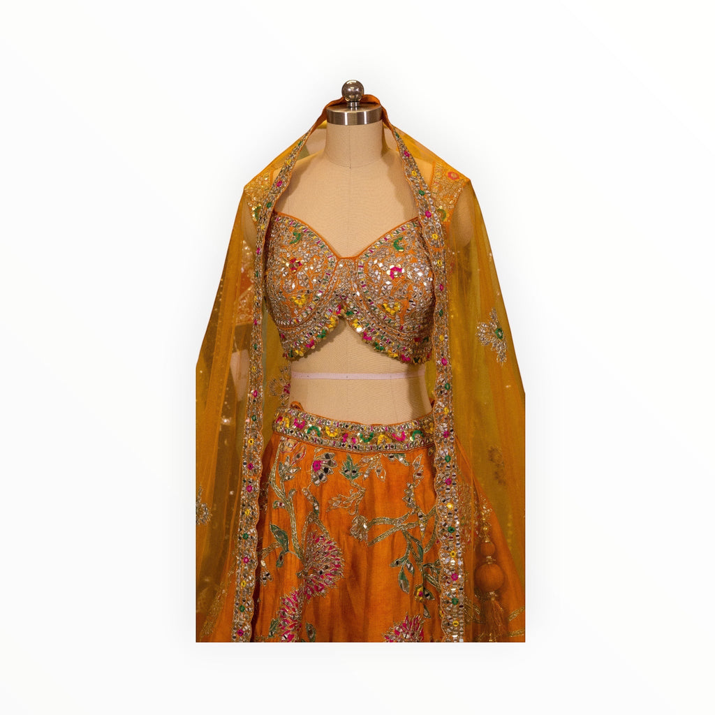 Zari Designs orange Carnival Lehnga with intricate mirror work, floral embroidery, and a matching sheer dupatta.