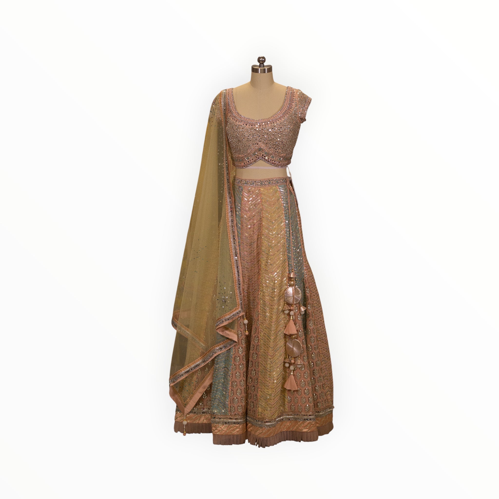 Zari Designs peach and pastel multi-colored lehenga choli with intricate mirror work, embroidery, and tassel details.