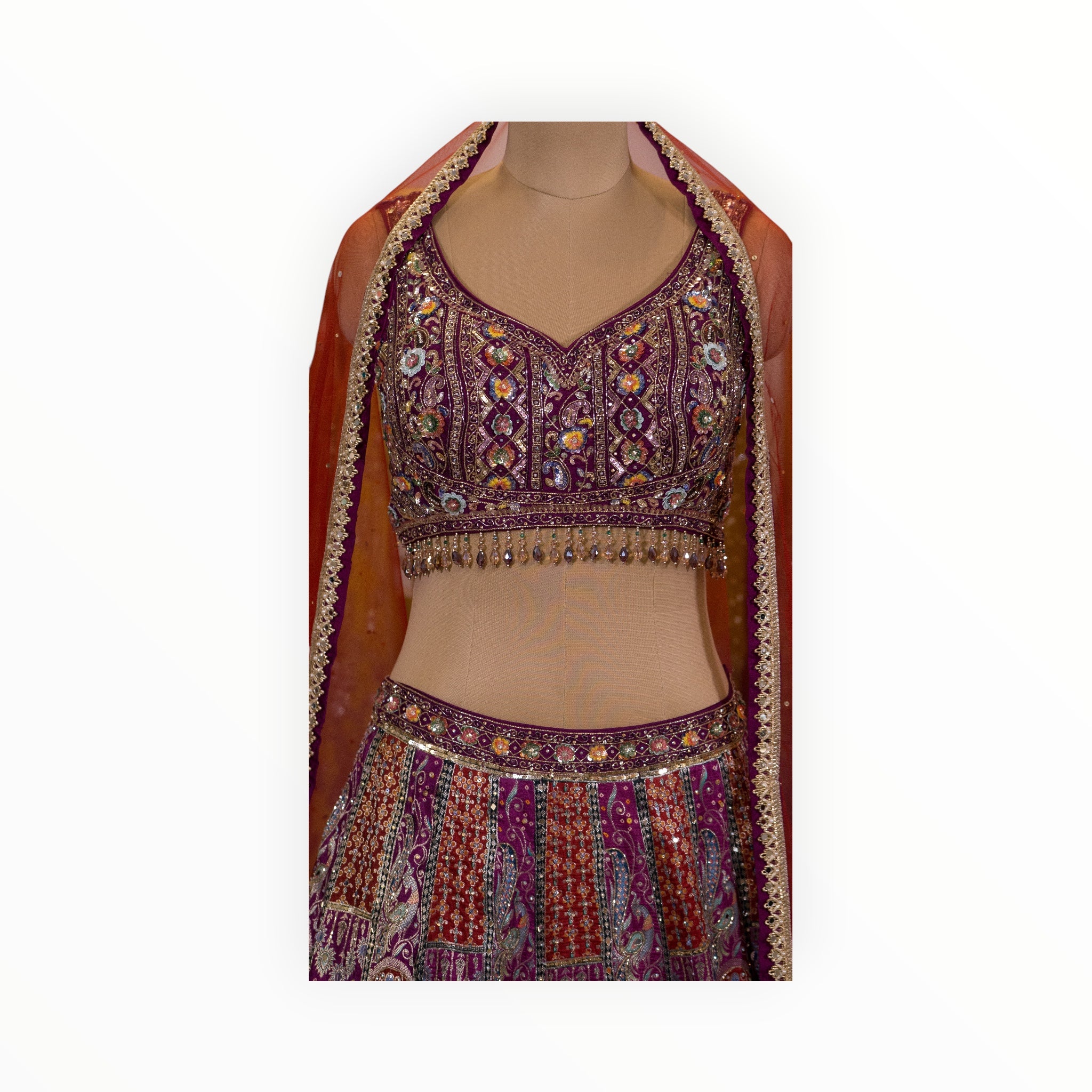 Zari Designs purple Banarsi lehenga with intricate floral embroidery, sequin work, and a matching orange dupatta.