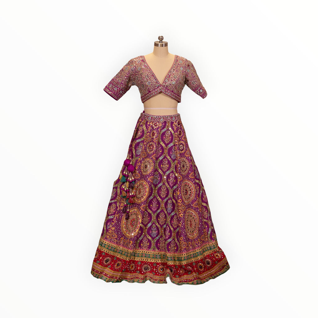 Zari Designs purple Carnival Lehnga with intricate gold embroidery, mirror work, and a deep V-neck blouse on a mannequin