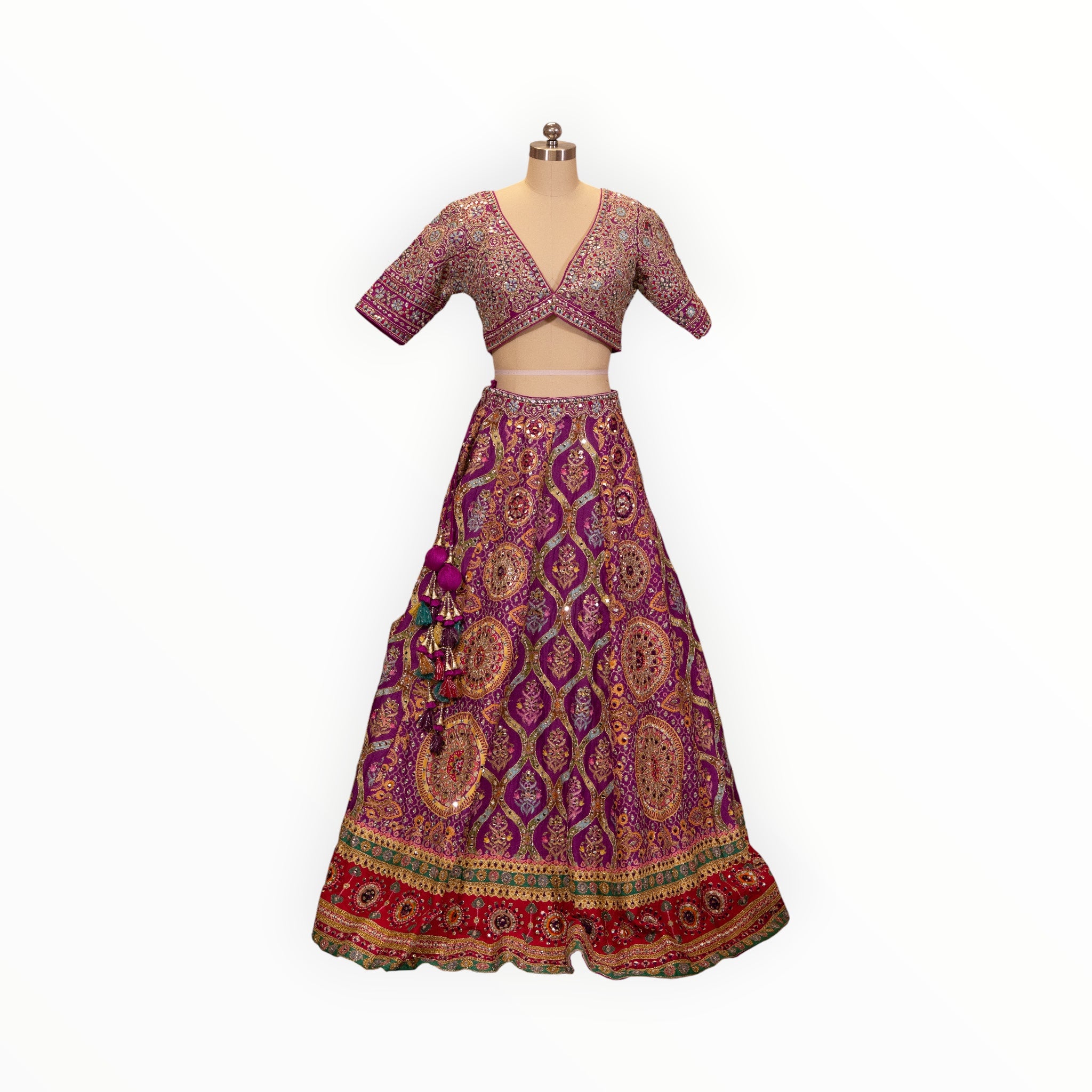 Zari Designs purple Carnival Lehnga with intricate gold embroidery, mirror work, and a deep V-neck blouse on a mannequin